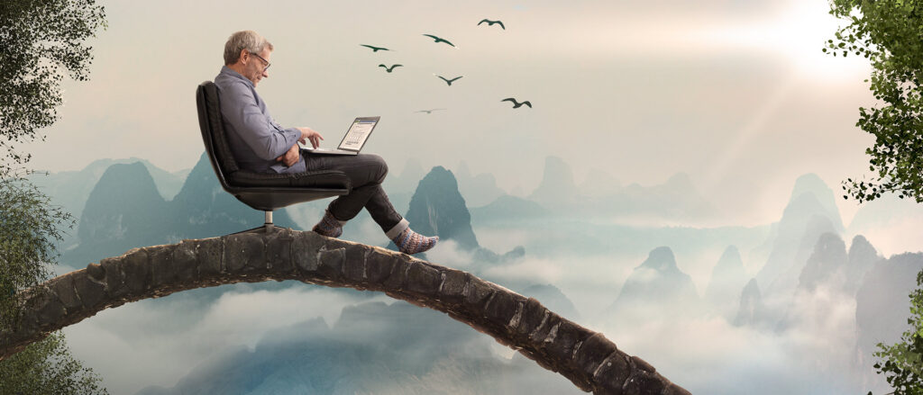 Mann sitzt mit seinem Laptop auf einem Baumstamm, denn in der neuen Arbeitswelt kannst du arbeiten wo du willst.